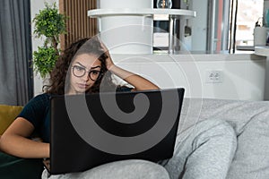 Young schoolgirl or college student teenage reading examination questions on her laptop because she is sick and cant go to school