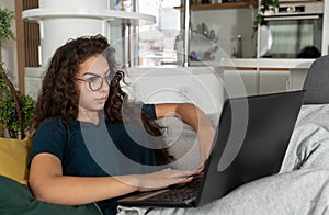 Young schoolgirl or college student teenage reading examination questions on her laptop because she is sick and cant go to school