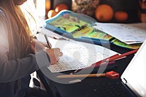 young schoolgirl does her writing exercises at home sise by side to parents working from home on laptop computer