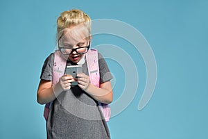 Young schoolgirl emotionally plays with smartphone and impairs vision