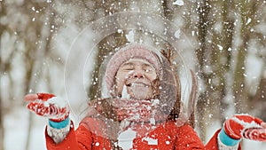 A young schoolgirl joyfully throws a snowball and breaks it with a palm when it falls. Emotions of joy. Winter fun in