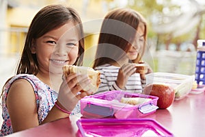 Young schoolgirls holding sandwiches at school lunch table photo