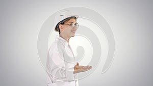 Young scientist in lab coat and hardhat walking and saying somet