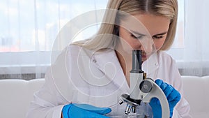 Young scientist laboratory assistant looks through a microscope in the laboratory. A young scientist is doing some