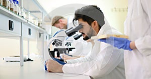 Young scientist looking through microscope in laboratory