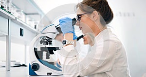 Young scientist looking through microscope in laboratory