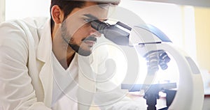 Mladý vědec hledá přes mikroskop v laboratoř 