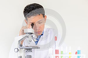 Young scientist looking through a microscope in a laboratory with white background, Children science concept