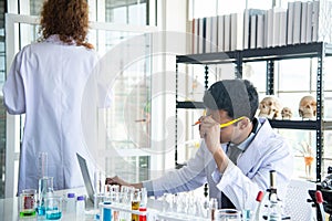 Young scientists or researchers wear eye glasses doing research in laboratory. Scientist working on computer and laboratory