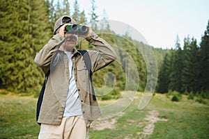 Young scout exploring nature using binoculars in forest