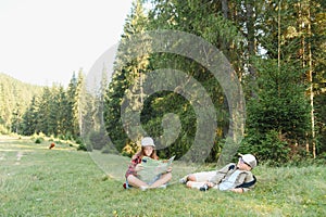 Young scouts exploring forest with map and binoculars
