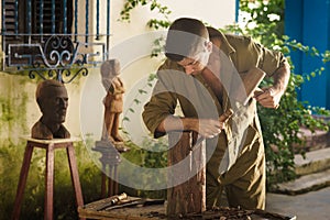 Young Sculptor Artist Working And Sculpting Wood Statue