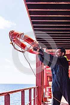 Young seafarer with lifebuoy on the cargo ship.