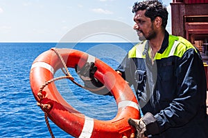 Young seafarer with lifebuoy on the cargo ship.