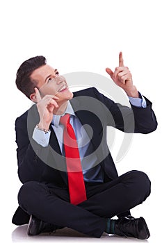 Young seated business man pointing