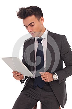 Young seated business man reading on his tablet