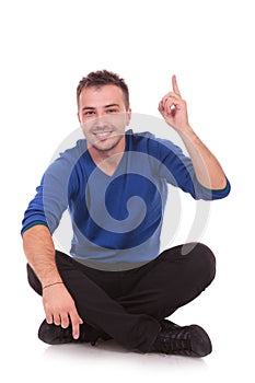 Young seated casual man pointing up