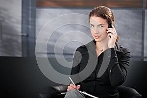 Young secretary talking on cellphone smiling