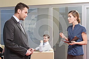 Young secretary talking to her boss in the office photo