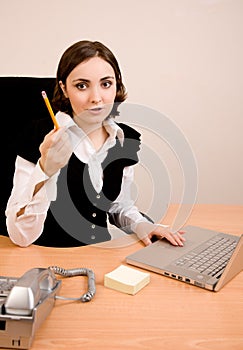Young secretary with telephone, laptop and pencil thinking