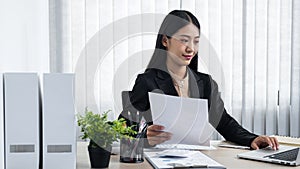 Young secretary woman holding paper document to typing email to her boss and clients