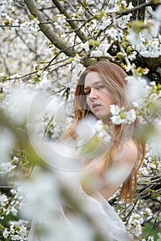 young seductive beauty redhead woman portrait, spring positive emotions in blooming apple tree blossoms