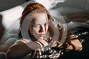 Young seductive sexy pretty redhead woman with coopery hair taking bath.