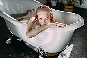 Young seductive sexy pretty redhead woman with coopery hair taking bath.