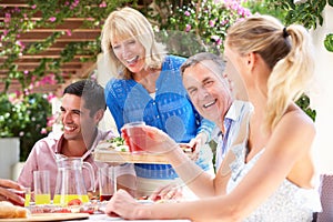 Young And Senior Couples Enjoying Family Meal