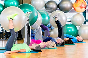 Young and senior people exercising with ball in gym