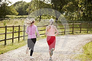 Young And Senior Women Enjoying Run Through Countryside Together