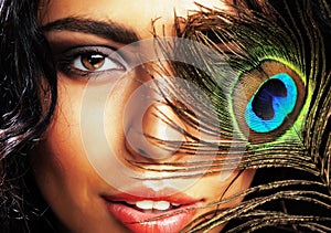 Young sensitive brunette woman with peacock feather eyes close u