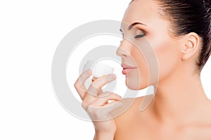 Young sensitive woman with closed eyes smelling cream