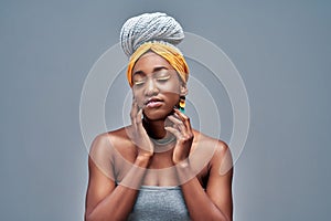Young sensual african american woman with artistic make-up tenderly touches her skin isolated on grey background