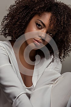 Young sensual african american woman in white shirt smiling and looking at camera