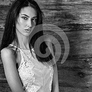 Young sensual & beauty brunette woman pose against wooden background. Black-white photo