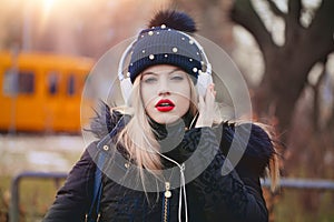 Young sensual blonde caucasian woman in winter cap listening mus