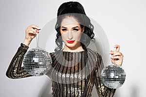 Young sensual brunette woman wearing evening dress and holding disco ball. Party time. Holiday concept.