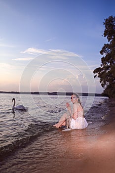 Young Sensual Sea Mermaid Blond Woman With Artistic Makeup and Strasses on Face Posing on Ocean Waves with Silver Crown And Net on