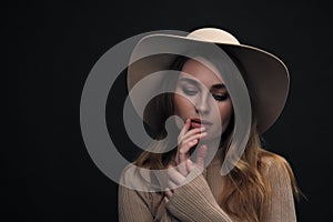 A young sensual sexy woman with a beautiful face and clear natural skin poses in the studio against a black background