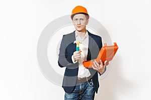 Young serious businessman in dark suit, protective construction helmet holding opened case with instruments or toolbox