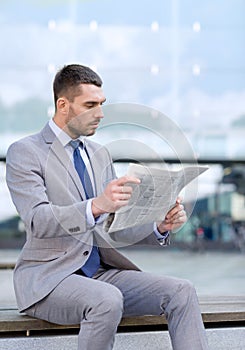 Young serious businessman newspaper outdoors