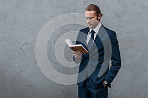 young serious businessman reading book in front of