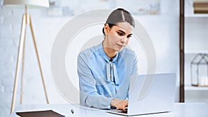 young, serious businesswoman typing on laptop