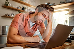 Young serious caucasian businessman working on a laptop from home alone. One stressed businessman looking unhappy while