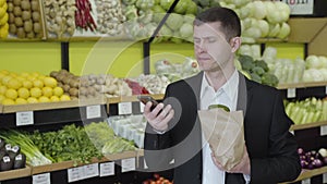Young serious Caucasian man hanging up the phone in grocery and sighing. Confident businessman in touch as making