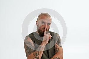 Young serious caucasian man showing silence sign
