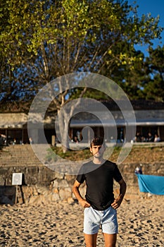 Young serious Caucasian man staring at the camera in the beach at sunset