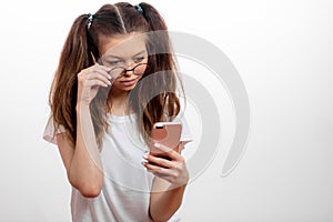 Young serious cute girl holding the cellphone and looking for the wi-fi