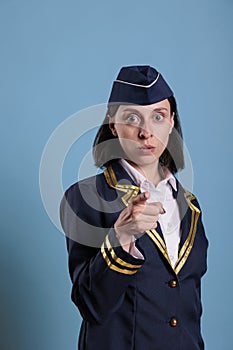 Young serious flight attendant pointing at camera with finger